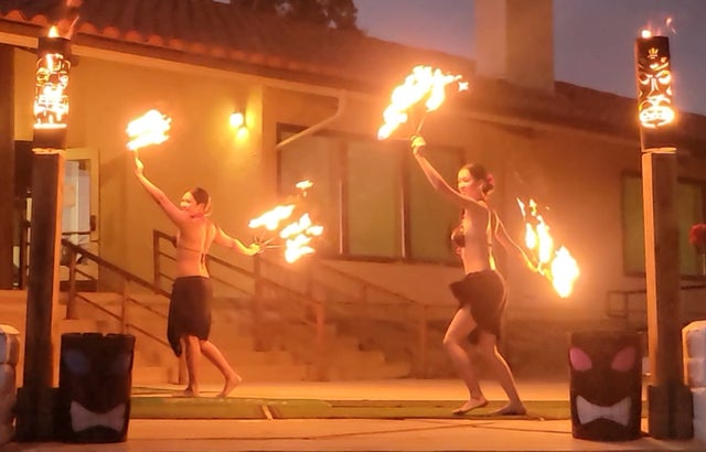Fire poi performer twirling flames at an outdoor night performance